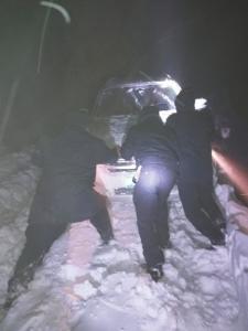 車陷雪中，民警徒手扒雪推車。