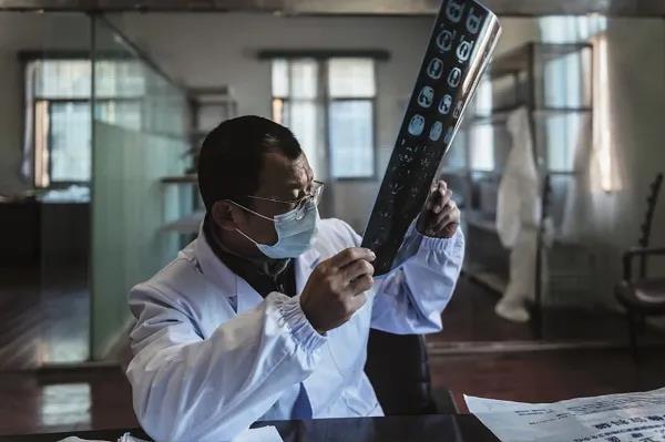 3月7日，硚口區六角亭街道社區衛生服務中心主任羅浩在一間臨時的辦公場所對著窗戶看CT片。